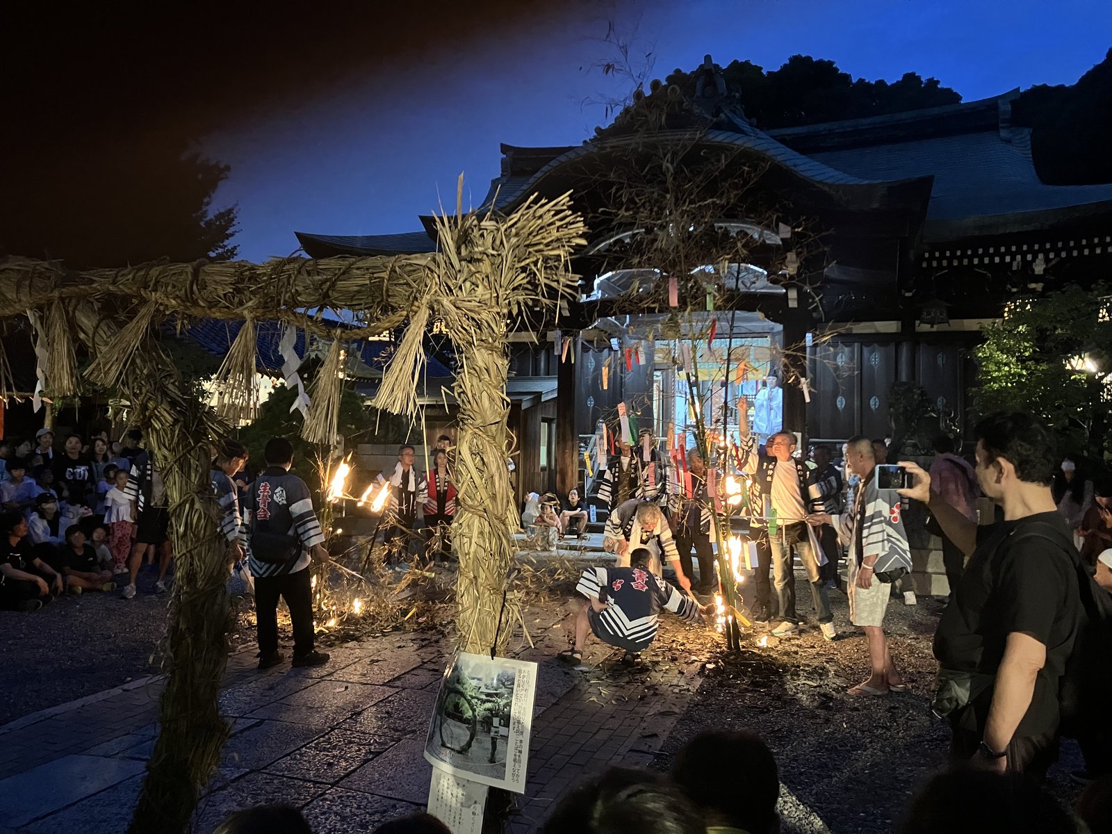 生根神社の茅の輪の前で、氏子たちが松明で笹を焚き上げる様子